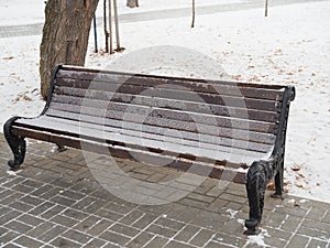 Snow covered park bench with first snow