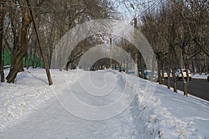 Snow-covered pedestrian sidewalk along the city road in winter.