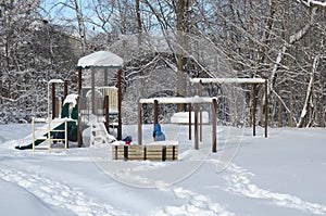 Snow-covered playground in a residential area with children playing