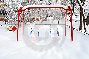 snow-covered public kids swing in winter