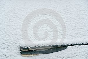 Snow covered rear windshield with wiper blades. Frozen snow on car in cold winter morning. Concept of driving in winter