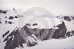 Snow covered ridge with small stream cascading over cliff