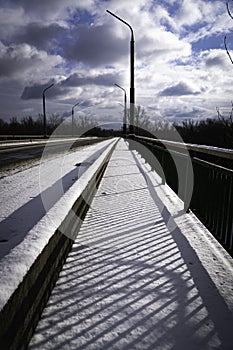 Snow-covered road on the bridge in the rays of the sun