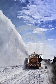 Snow-covered road cleaning by snow removal machine.