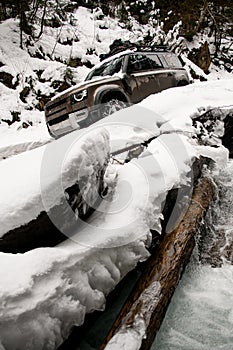 snow-covered road in the forest along which an off-road vehicle is successfully driving.