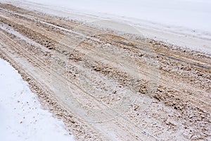 Snow-covered road mixed with mud, salt, chemical reagents and, traces of cars.