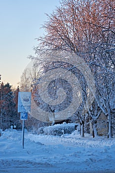 Snow-covered road sign and sidewalk on winter evening