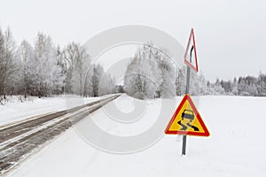 Snow-covered road and a sign warning about a dangerous section of the road