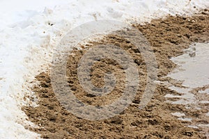 Snow-covered road sprinkled with sand at wintertime