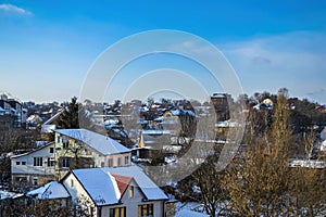 Snow-covered roofs of rural houses against the blue sky