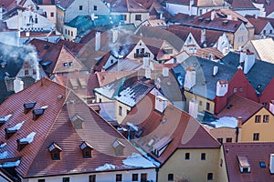 Snow covered rooftops from tiles, Smoke comming from chimneys on cold day. Pollution concept. Aerial cityscape view of