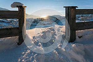 Snow covered rural winter landscape seen through fence during sunset, Wildermieming, Tirol, Austria