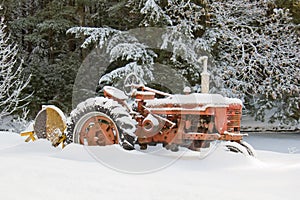 Snow covered rustic farm tractor