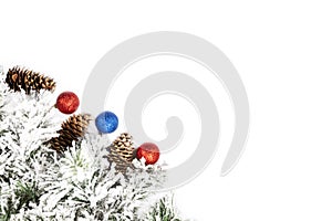 Snow-covered spruce decorative branch with cones and New Year`s balls on a white background. Space for text