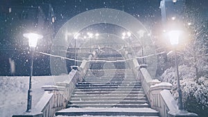 Snow covered stairs lit by glowing night lamps.