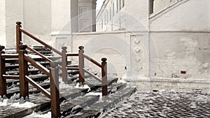 Snow-covered steps of the temple. Wooden staircase in winter. Snowy winter. The steps of the white-stone church, cleared of snow