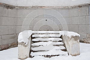 Snow-covered stone staircase near wall of old grey building with