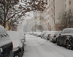 Snow-covered street with cars parked on both sides in the cold season, Bucharest, Romania.