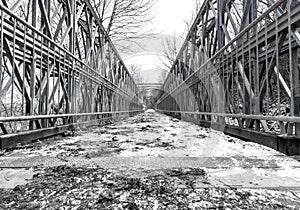 Snow covered symmetrical metal foot bridge in winter, balanced c