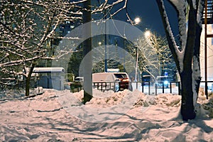 Snow-covered territory, trees, poles, fencing, cleaning facilities - a quiet winter evening, peace and tranquility.