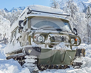 A snow-covered tracked SUV in the mountains in winter.