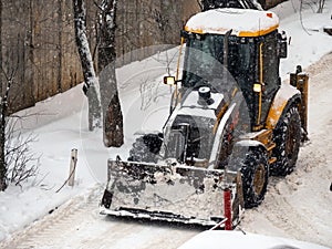 Snow-covered tractor lifting fresh snow during winter storm cleanup