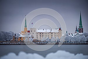 Snow-covered trees and view of the Riga Castle.