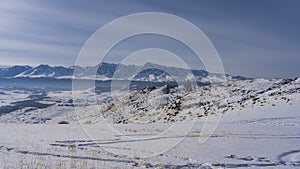 In the snow-covered valley, trampled paths and footprints are visible