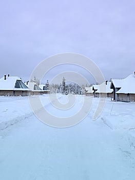 Snow-covered village, deer farm Lapinkyla on sunny winter day, Lapland, Northern Finland, rural houses with glass roofssnow