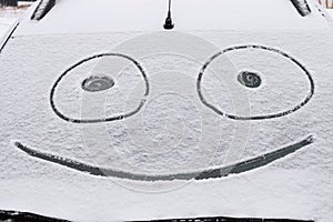 Snow covered windshield with drawn smile face