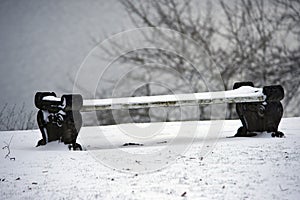 Snow-covered winter bench in a park