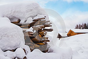 Snow covered wood stack and traditional wooden mountain huts