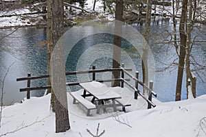 Snow covered wooden bench and table at Lame lake in Aveto Valley in winter time , in the hamlet of Rezzoaglio, province of Genoa, photo