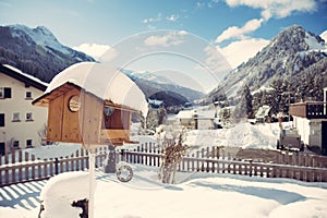 Snow covered wooden bird house on sunny winter morning.