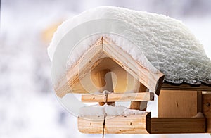 Snow covered wooden birdfeeder in winter