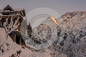 Snow covered wooden house in mountains - Majestic winter landscape in himalayas