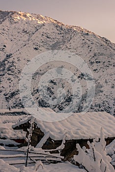 Snow covered wooden house in mountains - Majestic winter landscape in himalayas