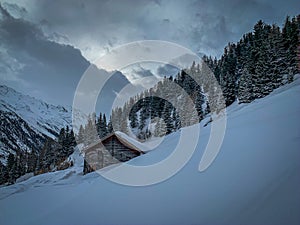 Snow covered wooden huts standing on a steep slope in the Ã–tztal valley in the Austrian Alps