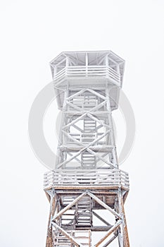 A snow-covered wooden lookout tower on top of the Czernica Mountain. Winter landscape in the Sudetes on a hiking trail