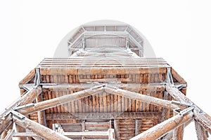 A snow-covered wooden lookout tower on top of the Czernica Mountain. Winter landscape in the Sudetes on a hiking trail