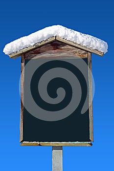 Snow covered wooden signpost and blue sky