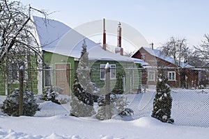 The snow covered yard of the wooden house in Belarus village. Old country house in winter