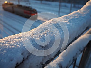 Snow, crust and frozen crust on metal railings. Suspension bridge over railway tracks. Harsh arctic climate. Abnormally