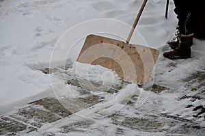 A snow disaster has covered places where snow is a rarity. girl clears the snow structure using the home method. wooden shovel in