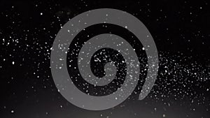 Snow dust against black background. Dynamic motion of white particles