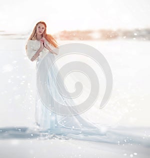 Snow fairy, the snow Queen. Girl in a white dress standing in the snow, wonderful way. Christmas fairy.