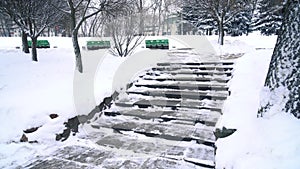 Snow falling against a background of park bench and frozen lake 4k