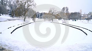 Snow falling against a background of park bench and frozen lake 4k