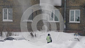 Snow falling from the roof in slow motion. Throwing white snow from the roof of a multi-storey building. Heavy seasonal