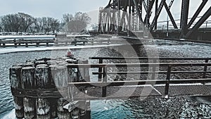 Snow falls in early dawn at the old historic swing bridge with the walkway extending out